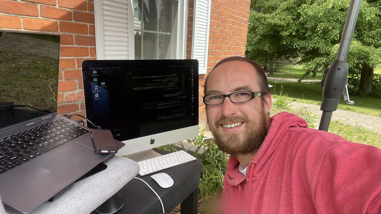 A 2017 iMac running code beside a laptop, set up outdoors.